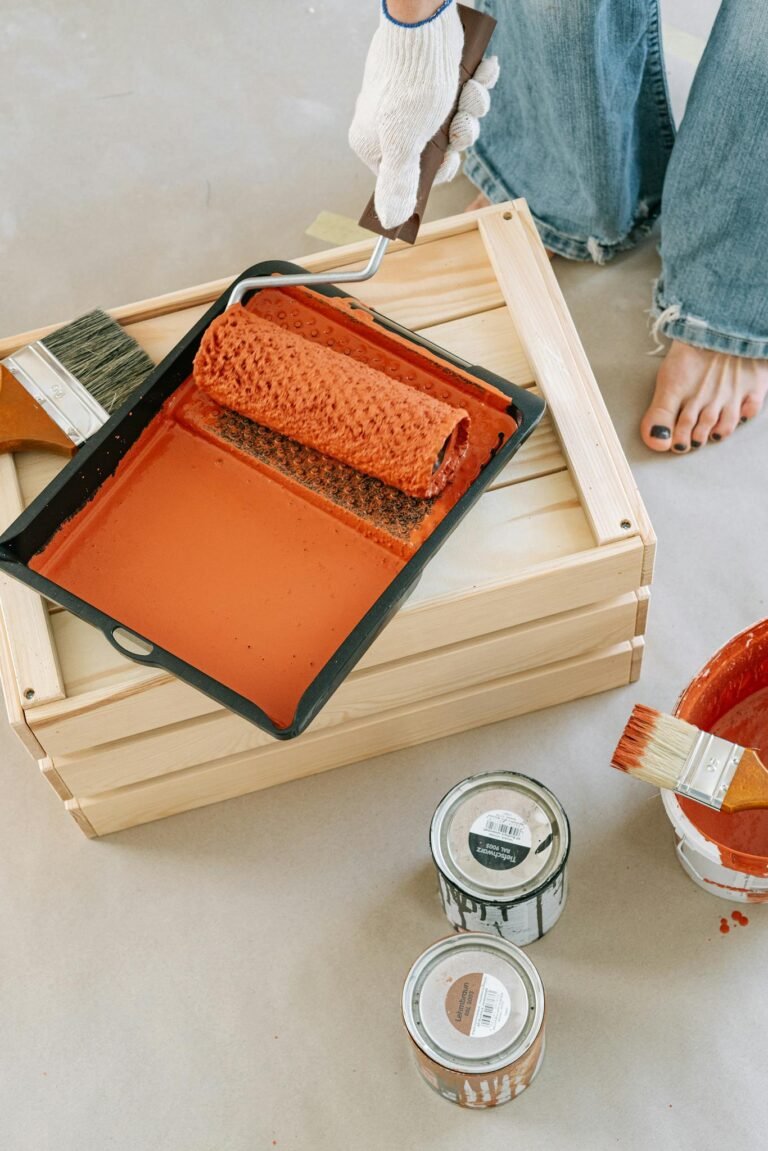 Close-up of paint roller in tray, ready for DIY home renovation project with wood crate and brushes.