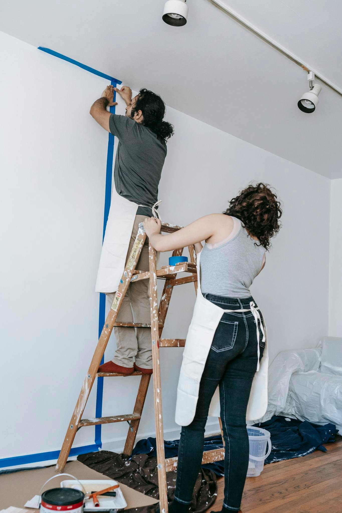 Couple working together on home renovation, painting walls in new apartment.